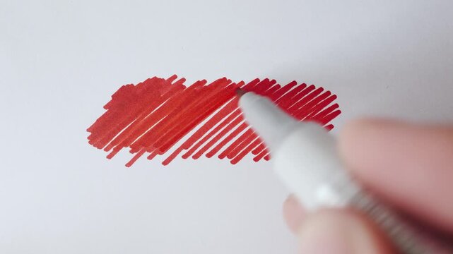 Red marker strokes and hatching cloud with real marker for text overlay on textured white paper close up.
