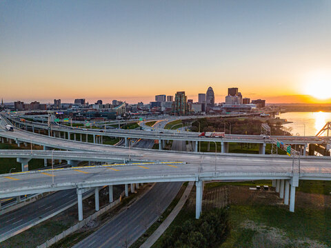 Aerial view of the complex highway interchange and city skyline at sunset with the river in the background in Louisville, Kentucky, United States.