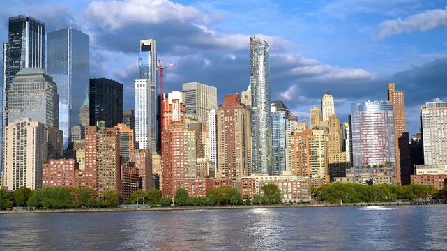 Varied buildings in the modern skyline of New York City. Low angle view rom the river. Dramatic clouds in the sky in the backdrop.