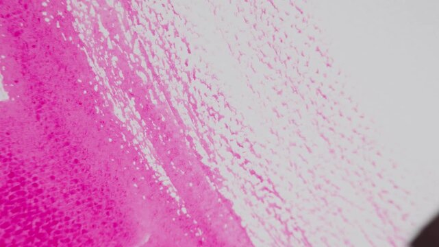 Close up of pink watercolour drawing paints on paper. Artist draws with a brush, liquid analog effects for background with copy space for text in center. 