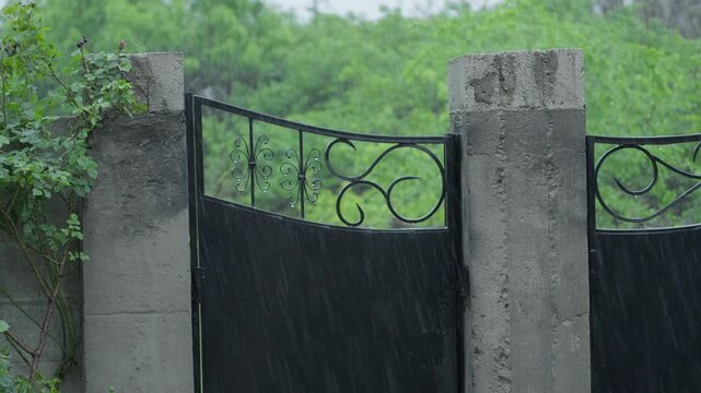 Heavy Rain Falling on Metal Gate and Concrete Fence Outdoors