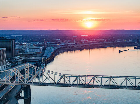 Aerial view of the George Rogers Clark Memorial Bridge spanning the Ohio River at sunset with the city skyline under a vibrant pink sky in Louisville, Kentucky, United States.