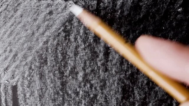 close up of chalk pencil drawing on textured black paper. slow motion footage. Background video can be used as overlay. doodling hatching