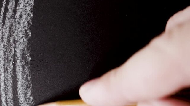 close up of chalk pencil drawing on textured black paper. slow motion footage. Background video can be used as overlay. doodling hatching