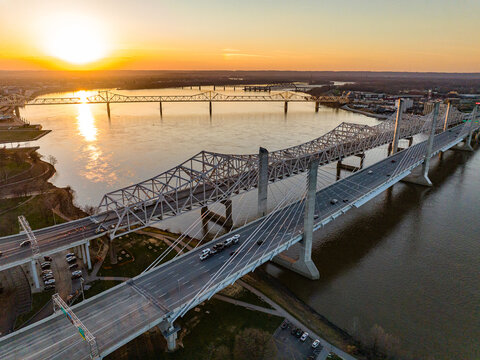 Aerial view of the Abraham Lincoln Bridge and Kennedy Memorial Bridge spanning the Ohio River during a vibrant sunset with traffic Louisville, Kentucky, United States.