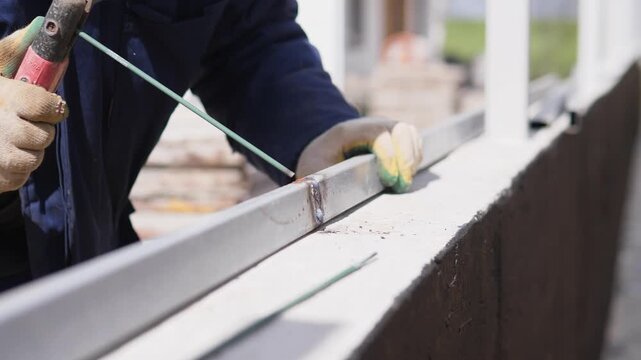 Closeup Welder Hands Arc Welding Bright, Intense Bluewhite Flare And Flying Sparks As Operator Feeds Electrode And Smooths Seam, Yellow Gloves And Heavy Jacket, Structural Steel Frame