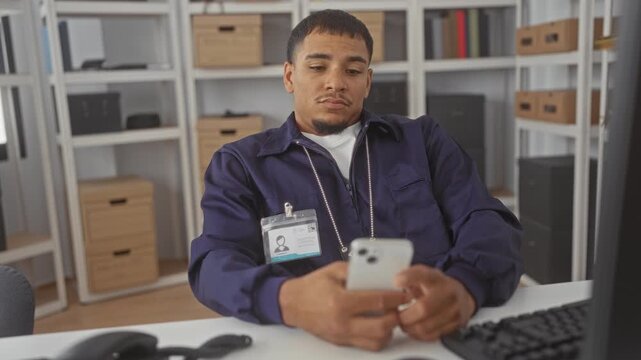 Man detective wearing badge holding smartphone and scrolling with hands in police building; weary duty.