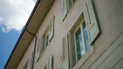 Obraz premium European apartment windows with open shutters viewed from low angle against sky expressing residential architecture perspective urban living and serene atmosphere