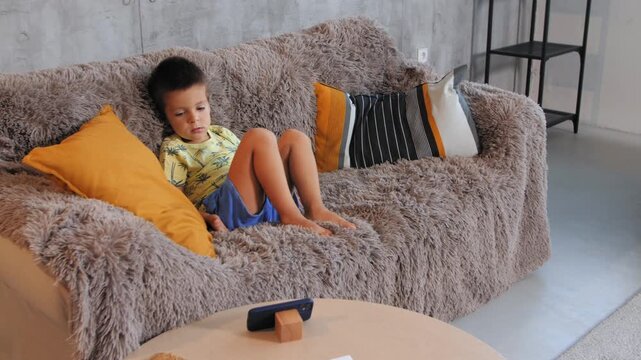 Mother bringing little daughter to older brother on sofa