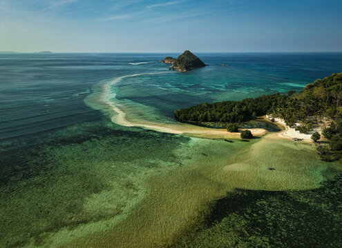 Aerial drone view of Lakdayan Sandbar near Coron Island, Philippines, featuring a curved tropical sandbar, turquoise coral reefs, crystal clear ocean water and a remote island landscape in Palawan.