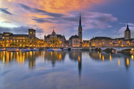 Local view of the illuminated old town of Zurich after sunset, reflection of the churches Fraum&uuml;nster and St. Peter in the river Limmat