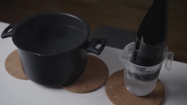 Crafting process of cutting glass bottle using thermal shock, alternating between cooling the glass with ice water and heating it with hot water, eventually causing clean break, close-up, slow motion.