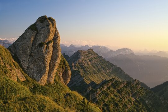 Striking rock in front of Mount Federispitz in the atmospheric evening light, behind it the Central Swiss Alps, Canton St. Gallen, Switzerland
