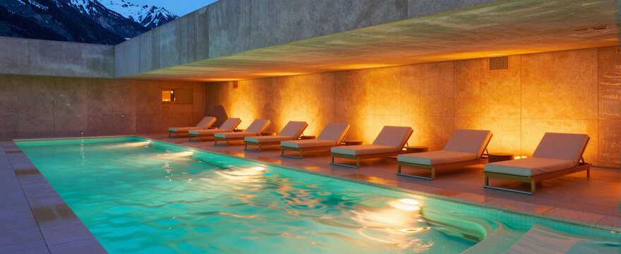 Warm pool area at dusk with lounge chairs under warm light.