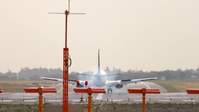 Commercial aircraft with unrecognizable livery landing, touchdown and braking, rear view. Flight arriving. Travel concept