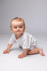 Fototapeta premium baby in a white bodysuit is smiling on a white background in the studio