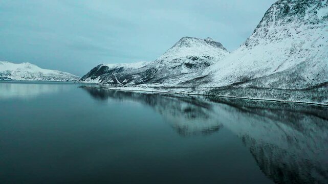 R&uuml;ckw&auml;rtsflug &uuml;ber arktischen Fjord und verschneite Berge in Norwegen