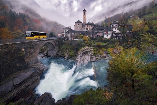 Village view of Lavertezzo on a rainy autumn day, post bus crossing a stone bridge, Verzasca Valley, Canton Ticino, Switzerland