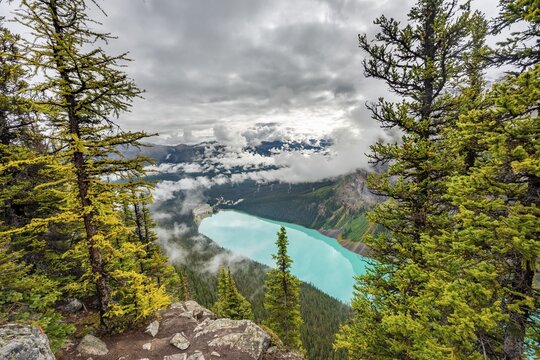View of turquoise glacial Lake Louise, summit of The Beehive, cloudy mountain landscape, Banff National Park, Alberta, Canada