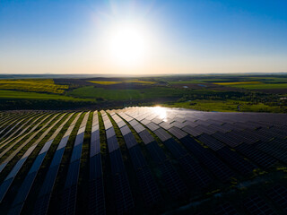 Fototapeta premium Solar panels cover a large field in a rural area during sunset in Spain, capturing sunlight for clean energy production in the early evening