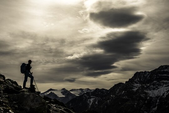 Climbers on rocks in backlight with cloudy sky in the background South Tyrolean mountains, Martell valley, Merano, Vinschgau, South Tyrol, Italy