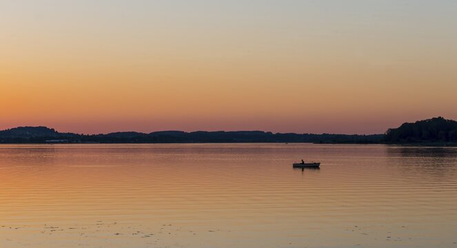 Sunset at Lake Chiemsee, fisherman on a rowing boat, Prien, Bavaria, Germany