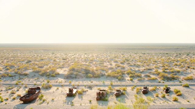 Aerial view of Moynaq Ship Graveyard Uzbekistan. Rusted Soviet-era fishing vessels and trawlers sit stranded in the Aralkum Desert. Environmental disaster and lost maritime heritage in Muynak