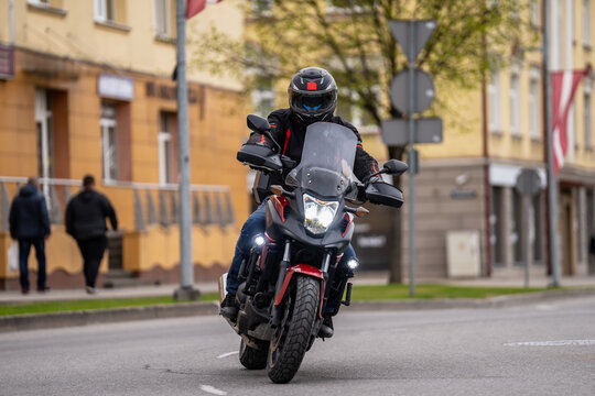 Biker in protective apparel operating a powerful bagger motorcycle on city pavement showcasing motorcycling lifestyle and modern automotive technology