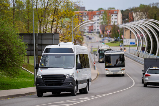 Delivery van and commuter buses navigating a paved highway in a European city environment, showcasing traffic flow, municipal services, and modern street architecture