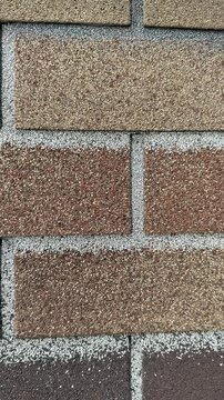 Close-up ondulin cottage roof shingles showing granular texture and mortar lines, weathered earthy tones, asphalt granules