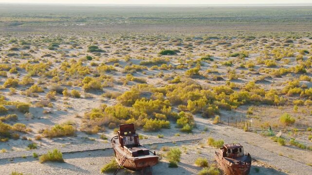 Aerial view of Moynaq Ship Graveyard Uzbekistan. Rusted Soviet-era fishing vessels and trawlers sit stranded in the Aralkum Desert. Environmental disaster and lost maritime heritage in Muynak
