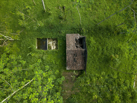 Aerial view of Houses Damaged by Mount Merapi Eruption with collapsed roofs surrounded by dense green forest Cangkringan, Special Region of Yogyakarta, Indonesia.
