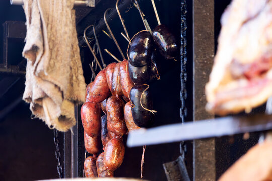 Traditional chorizo and blood sausages hang from metal hooks.