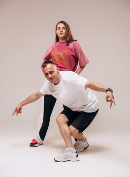 Young male and female hip hop dancers posing and dancing on a gray studio background. Urban street style and modern dance concept.