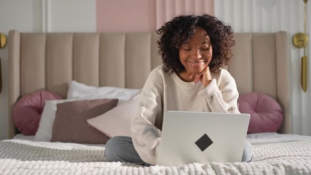 African American girl using laptop in bed at home office typing chatting reading writing email. Young black woman having virtual meeting online chat video call conference. Work learning from home