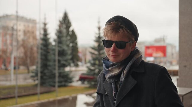 City balcony smile of white creator in scarf and sunglasses, relaxed candid moment with pine trees and overcast sky approachable lifestyle creator energy, soft diffuse light, cozy knit beanie
