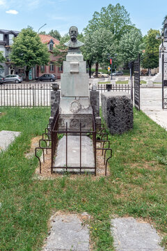Burial site of Stanko S. Ivanovic at the historic Vlaska Donjokrajska Church cemetery. An ancient stone stecak stands next to the memorial bust in the park area. Cetinje, Montenegro - June 20, 2021
