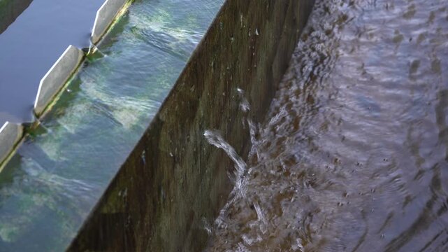 Close-up of a water leak jetting from a cracked concrete wall in a wastewater clarifier tank. Essential B-roll for projects highlighting aging infrastructure, facility maintenance, and water loss.