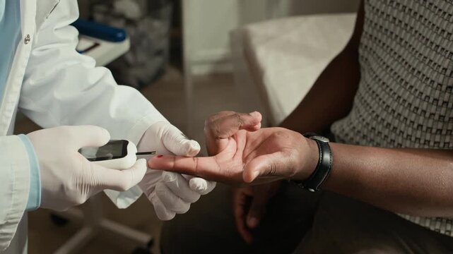 Cropped shot of male doctor checking blood sugar levels with glucometer on patient finger during diabetes appointment in medical office