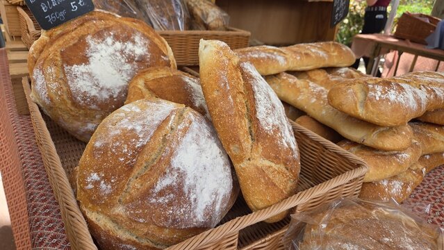 Round sourdough loaves and baguettes dusted with flour on wicker baskets for bakery menu banner and rustic food market background