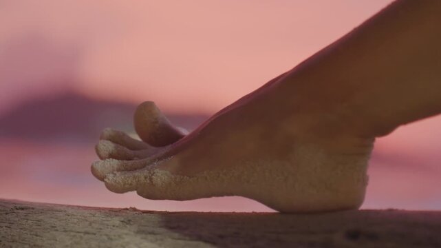 Beach toes glow. Sunset sands under bare feet. Relaxed twilight ambiance with grains on sandy toes. Closeup of barefoot steps along shoreline bathed in sunset pink glow and sandy textures