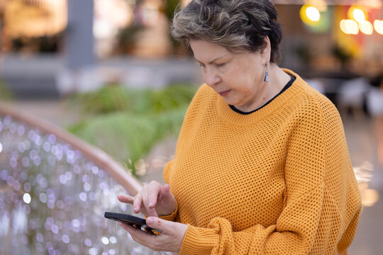 Senior woman having serious phone call indoors, expressive gesture and focused look, communication and lifestyle concept.