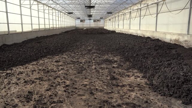 Cinematic panning shot across a massive bed of drying biosolids in a solar greenhouse. Essential wide-angle B-roll for projects on ESG, the circular economy, and sustainable waste management.