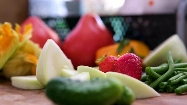 Cucumbers, sliced pattypan squash, green beans, pink tomatoes, flowers, and tender young zucchini create a natural healthy vegan food scene with rustic homemade atmosphere and seasonal harvest mood. 
