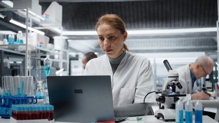 Naklejka premium Sick lab expert rubbing head temples, feeling ache while working on laptop, studying genomics. Fatigued laboratory technician hurting while studying DNA strand mapping on notebook, camera A