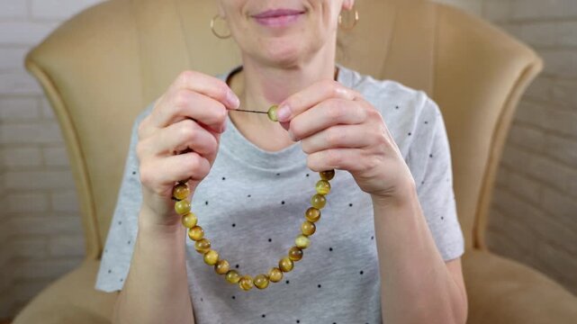 Woman holding a tiger's eye rosary. Woman is counting yellow tiger's eye rosary beads for stress relief