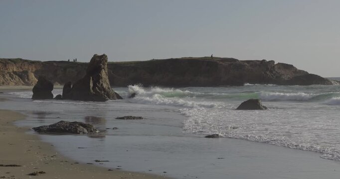 Silhouetted figures on a coastal bluff overlooking a sea stack in Fort Bragg