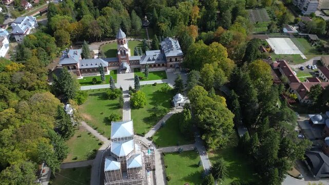 Drone aerial view of a beautiful Eastern Orthodox church surrounded by lush parkland, monastery buildings, and landscaped gardens. Scenic overhead perspective showcasing religious architecture, peacef