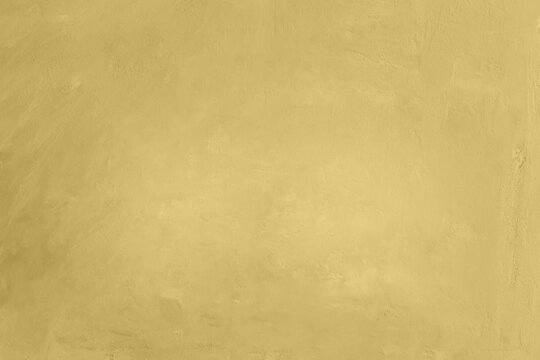 Detailed texture of warm yellow or mustard plaster wall with elegant lighting vignette. Minimalist warm background.