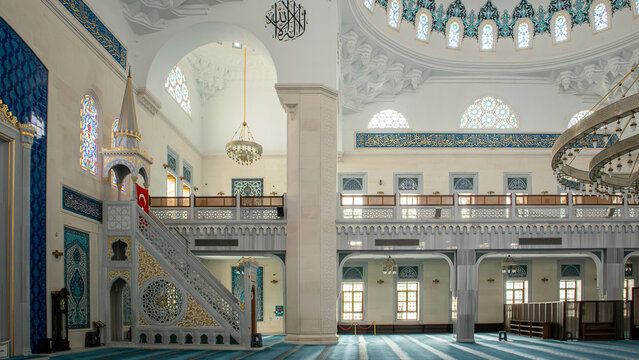 Elegant mosque interior features marble minbar with golden accents and Turkish flag in a setting with arched galleries